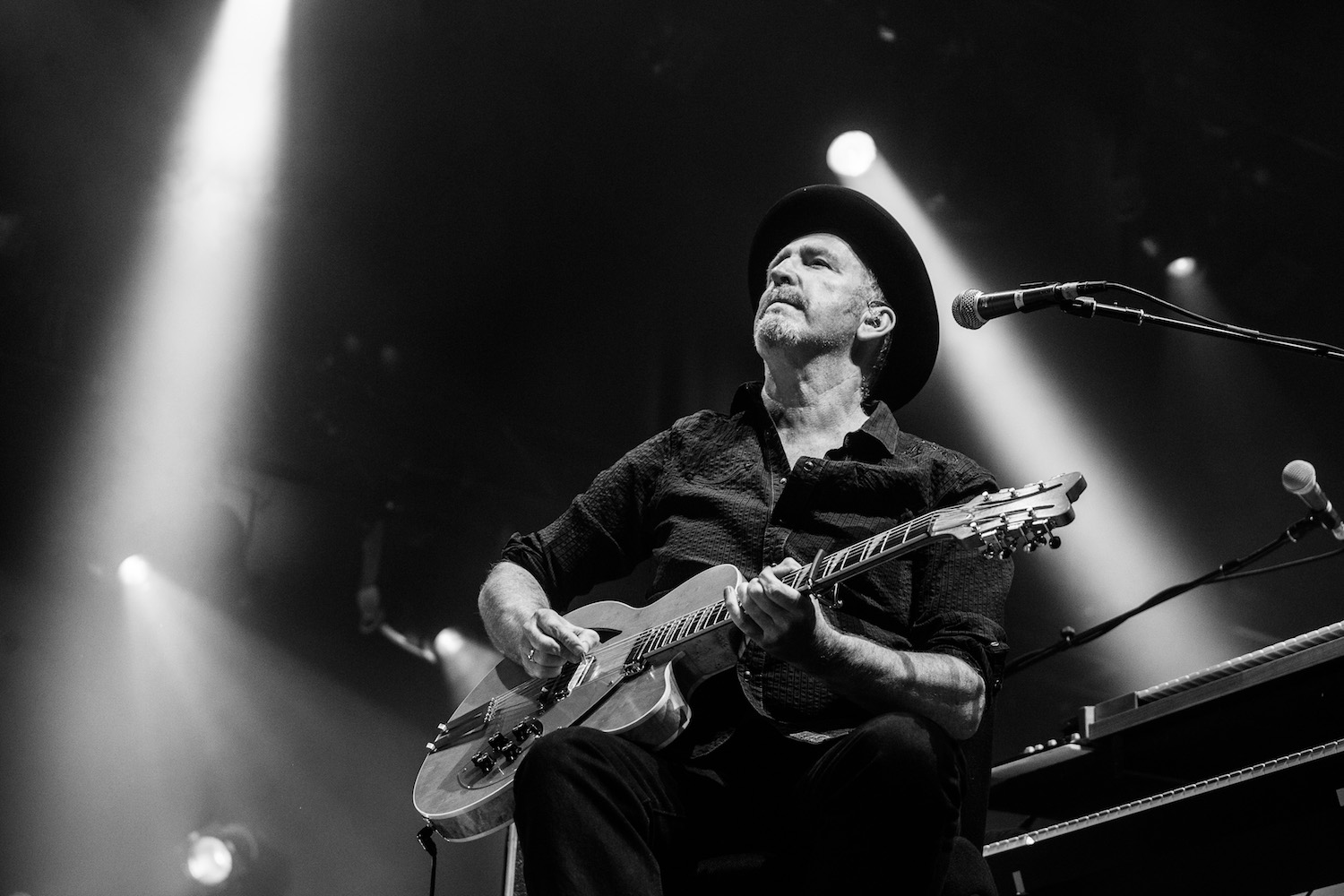 Black and white image of Jim Moginie playing guitar